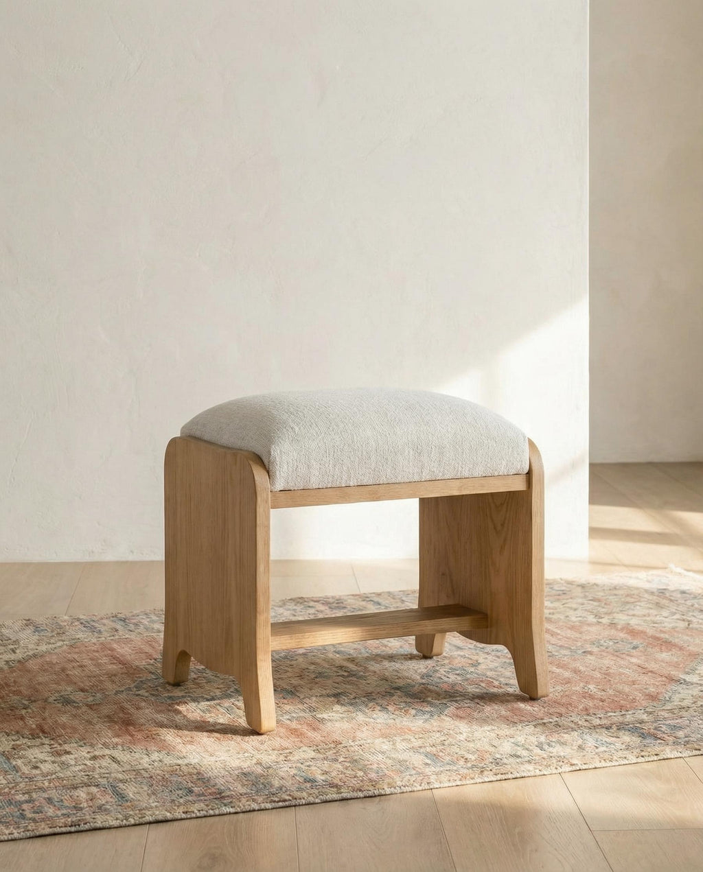 Wooden stool with a cushioned seat on a patterned rug