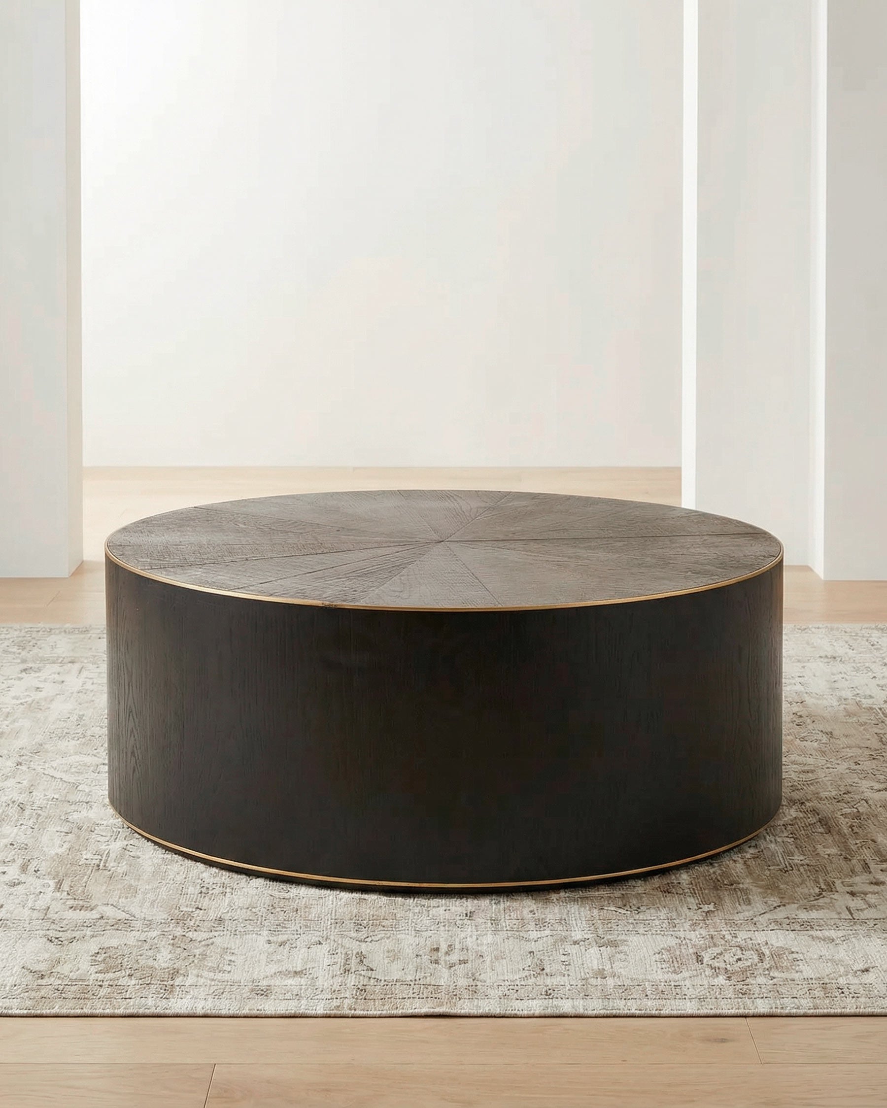 Round oak & brass coffee table in a room with light-colored walls and flooring.