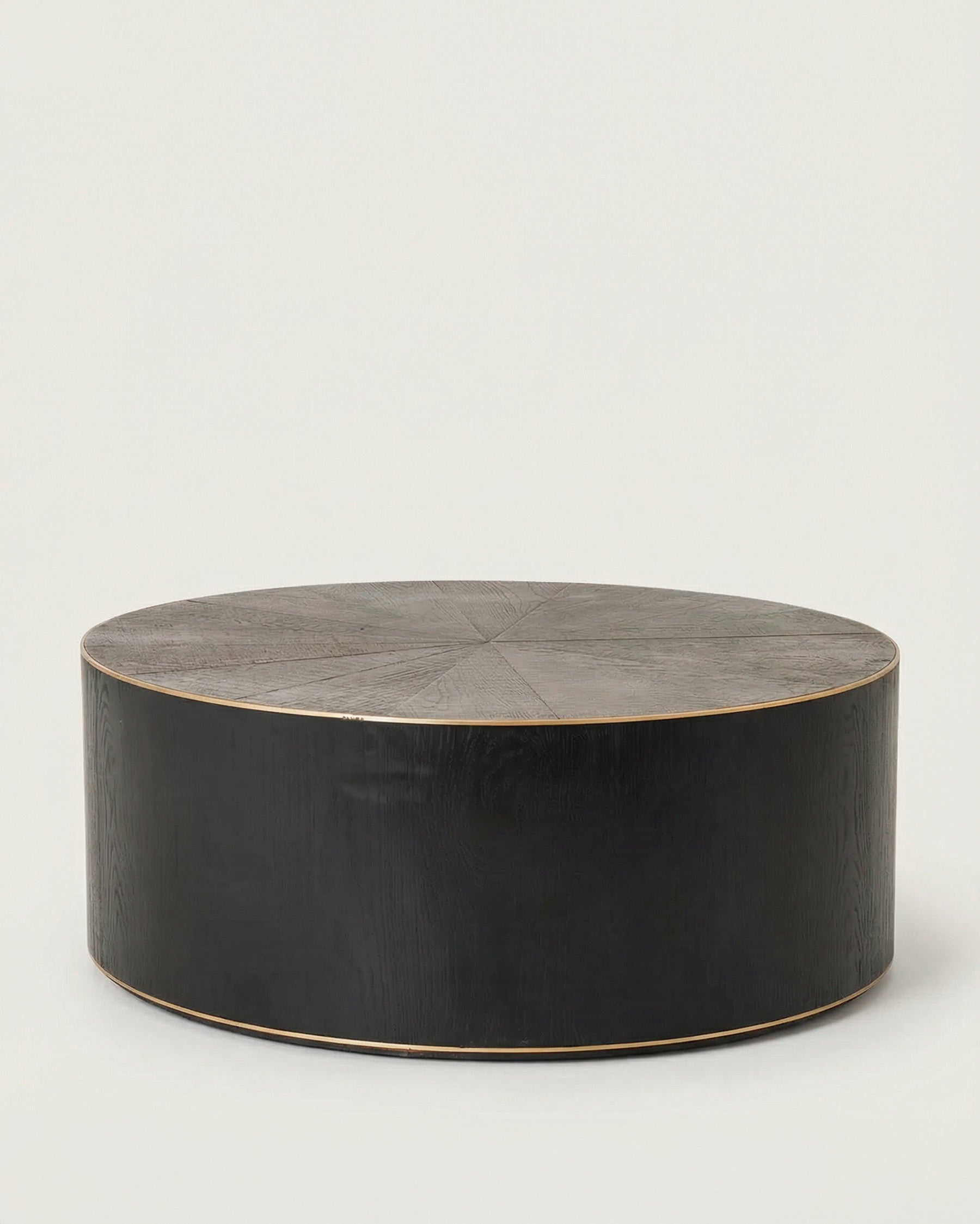 Round oak and brass coffee table with a textured surface on a light gray background